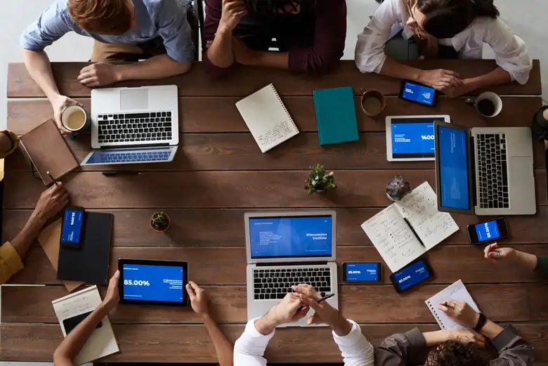 A team working together around a table with laptops, tablets and phones